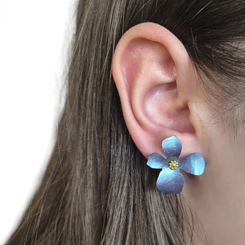 Przestrzenne kolczyki z tytanu i srebra w kolorze turkusowo jeansowem o zmiennej kolorystyce, zależnej od kąta padania światła - przykład noszenia